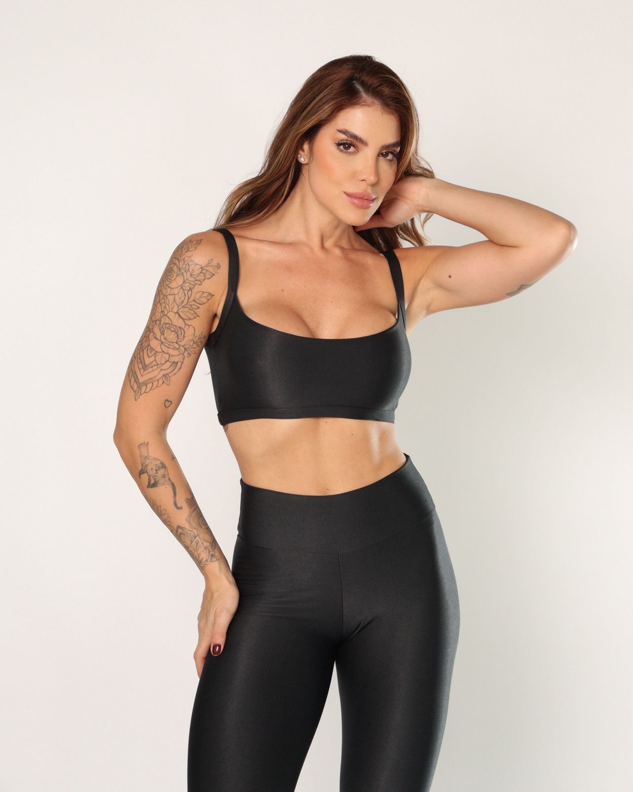 Woman wearing a black sports bra and leggings against a light background