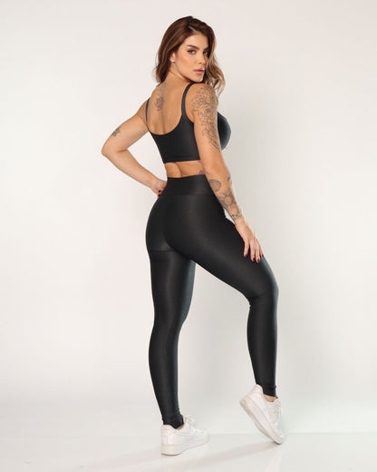 Woman wearing black leggings and sports bra on a white background