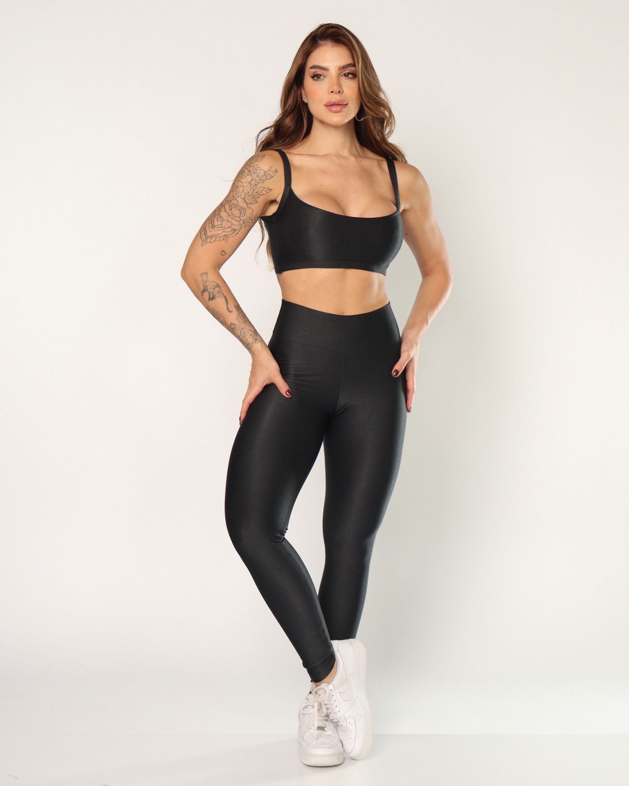 Woman wearing black leggings and sports bra on a white background